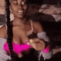 a woman in a pink top is sitting on a bed holding a pink toy .