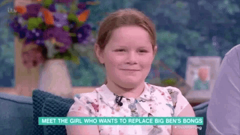 a young girl is sitting in front of a microphone on a television show and smiling .