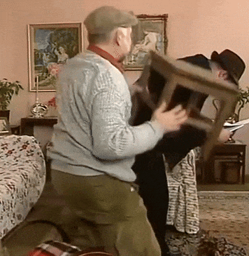 a man in a hat is holding a chair over another man