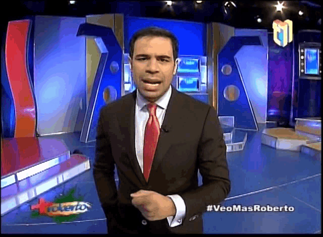 a man in a suit and tie is standing in front of a screen that says veomasroberto