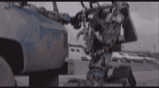 a robot is standing in front of a blue truck .
