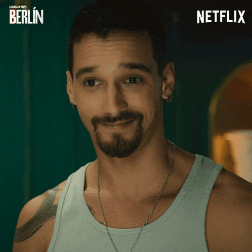 a man with a beard is smiling in front of a poster for berlin