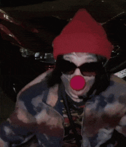 a close up of a person wearing a clown costume and holding a glass .