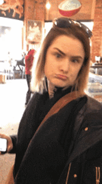 a woman wearing sunglasses and a black jacket looks at the camera