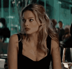 a woman is sitting at a table in a restaurant wearing a black tank top .