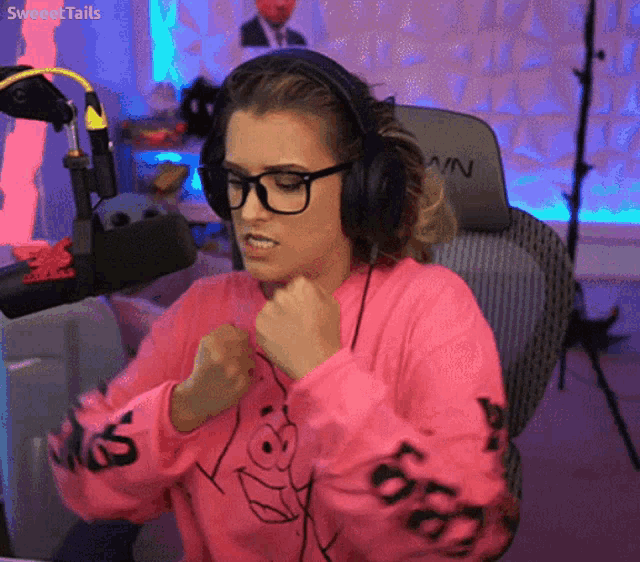 a woman wearing headphones and a pink sweater that says sweettails on the sleeves