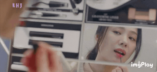 a woman applying lipstick in front of a mirror with khj written on the bottom right