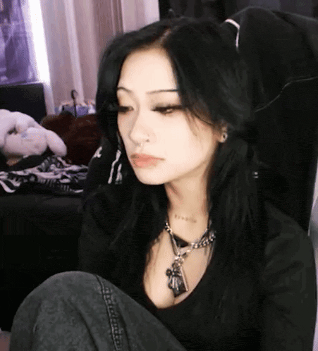 a woman with long black hair is wearing a necklace and a nose ring .