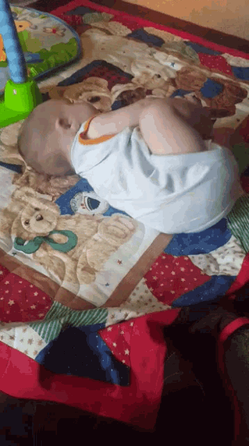 a baby is sleeping on a quilt with teddy bears on it