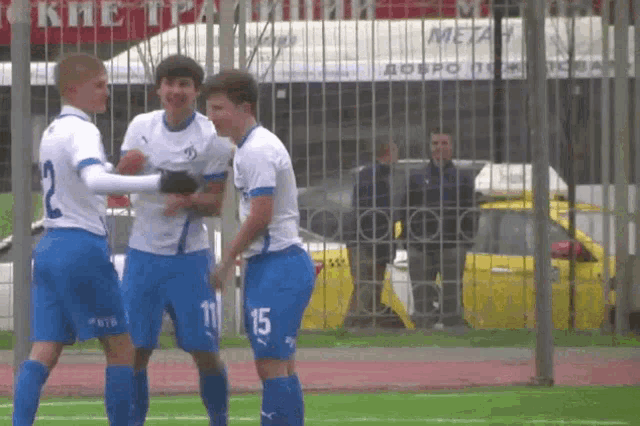 a soccer player with the number 15 on his shorts is being hugged by two other players