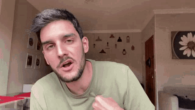 a man with a beard wearing a green shirt is making a funny face