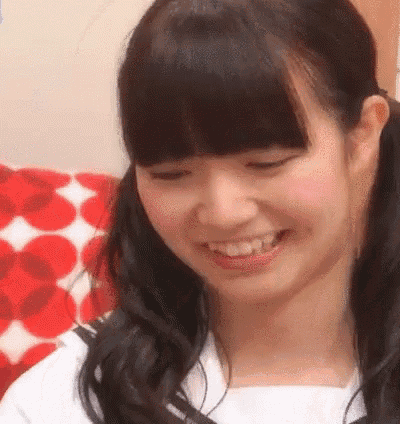 a young girl with pigtails is smiling while sitting on a red and white polka dot couch .