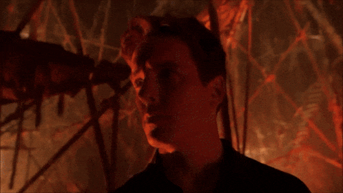a man in a forest says have some punch in front of a fire