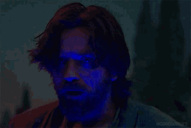 a man is standing in the dark with a blue light shining on him .