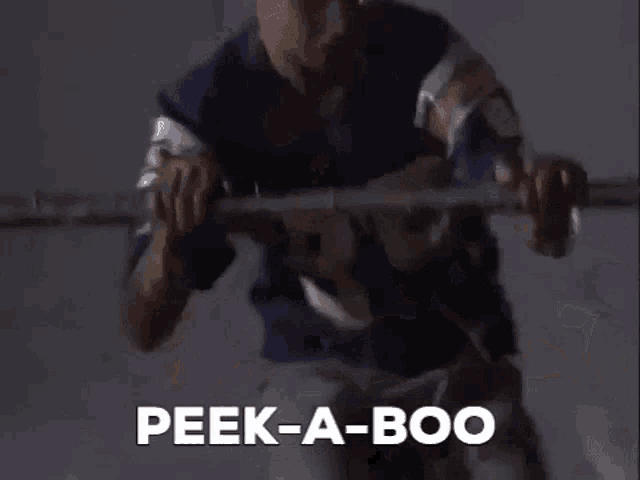 a man is standing in a dark room holding a hanger and saying peek-a-boo .