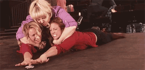 a group of women are laying on the floor wrestling each other .