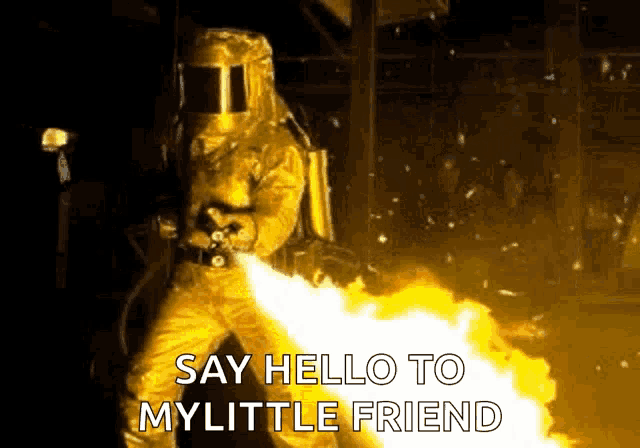 a man in a yellow protective suit is holding a flamethrower and saying `` say hello to my little friend '' .