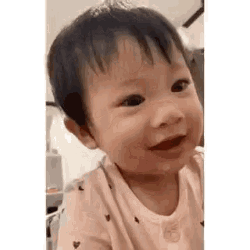 a baby is smiling and looking at the camera while sitting in a room .