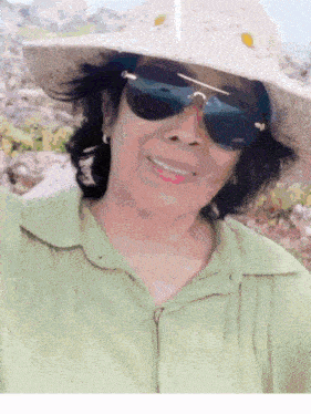 a woman wearing sunglasses and a hat is smiling