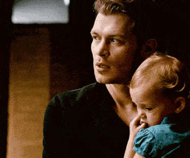 a man in a black shirt is holding a baby girl in his arms