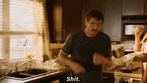 a man in a kitchen with the word shit written on his shirt