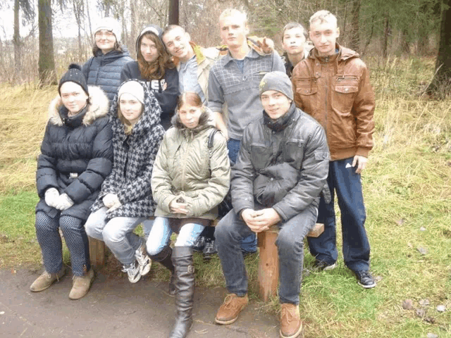 a group of young people posing for a picture with one wearing a jacket that says adidas on it