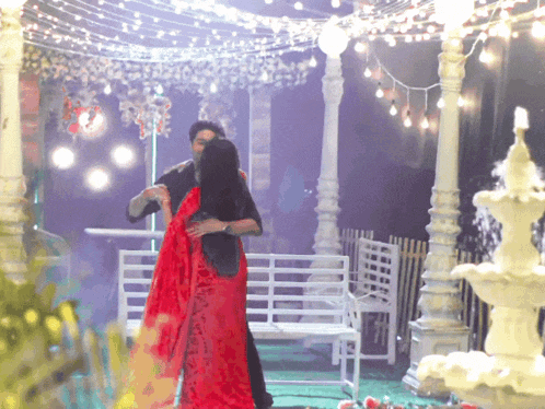 a man and woman are dancing under a gazebo with lights
