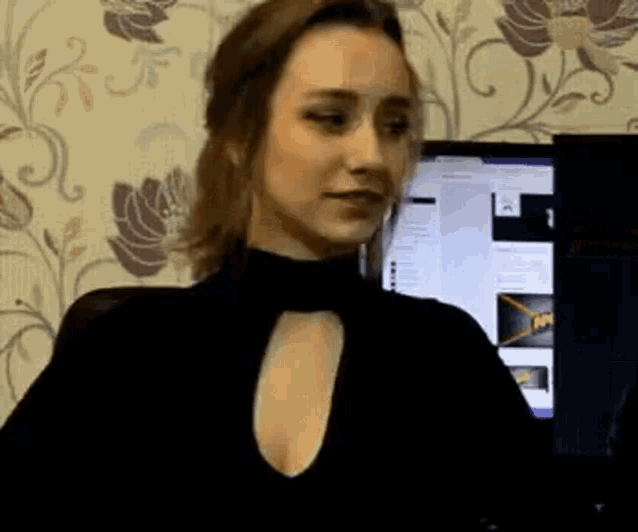 a woman in a black dress is sitting in front of a computer .