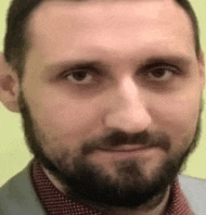 a close up of a man 's face with a beard and a suit and tie .