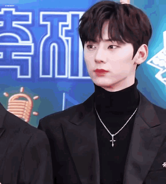 a man wearing a turtleneck and a necklace with a cross pendant