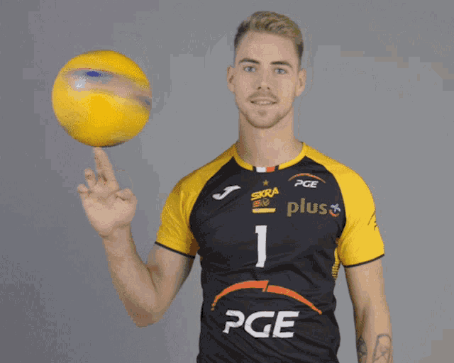 a man wearing a pge jersey holds a yellow ball