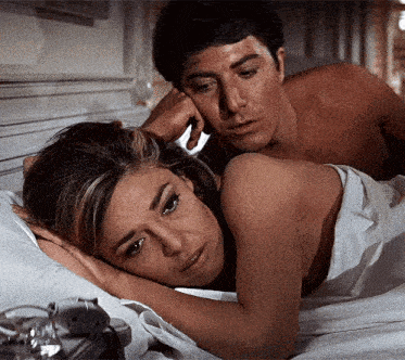 a man and a woman are laying in bed and the man is touching the woman 's hair