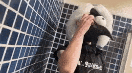 a person is taking a shower with a stuffed animal mask on their head .