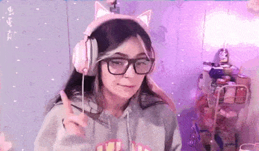 a girl wearing headphones and glasses is giving a peace sign in a room .