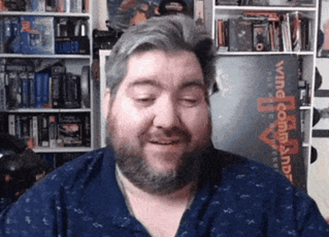 a man with a beard is smiling in front of a sign that says wing commander