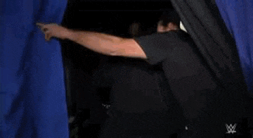 a man is standing next to a black car in a room .