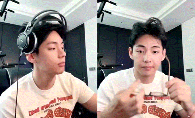 a young man wearing headphones is holding a pair of glasses in his hand .