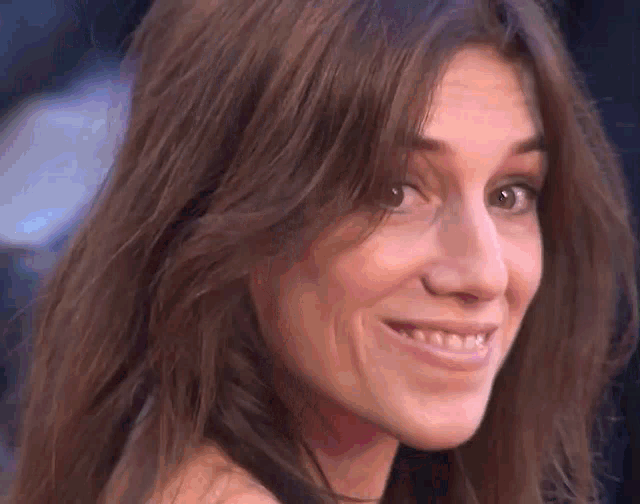 a close up of a woman 's face with long hair smiling .
