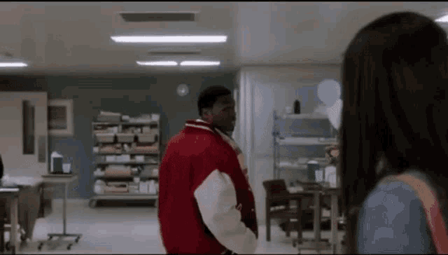 a man in a red jacket is standing next to a woman in a hospital .