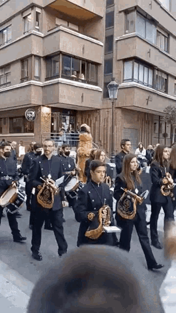a marching band is marching down a street in front of a building with a sign that says ' a ' on it