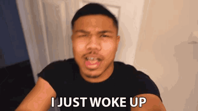 a man in a black shirt is making a face and says i just woke up