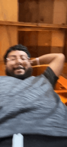 a man with a beard and glasses is laying down with his hands behind his head