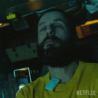 a man with a beard wearing a yellow shirt that says netflix on it
