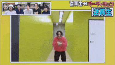 a man in a red sweatshirt is standing in a hallway with a group of people behind him .