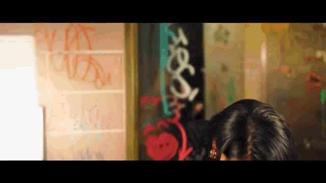 a woman standing in front of a wall with graffiti on it