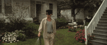 a man wearing sunglasses is spraying the grass in front of a house