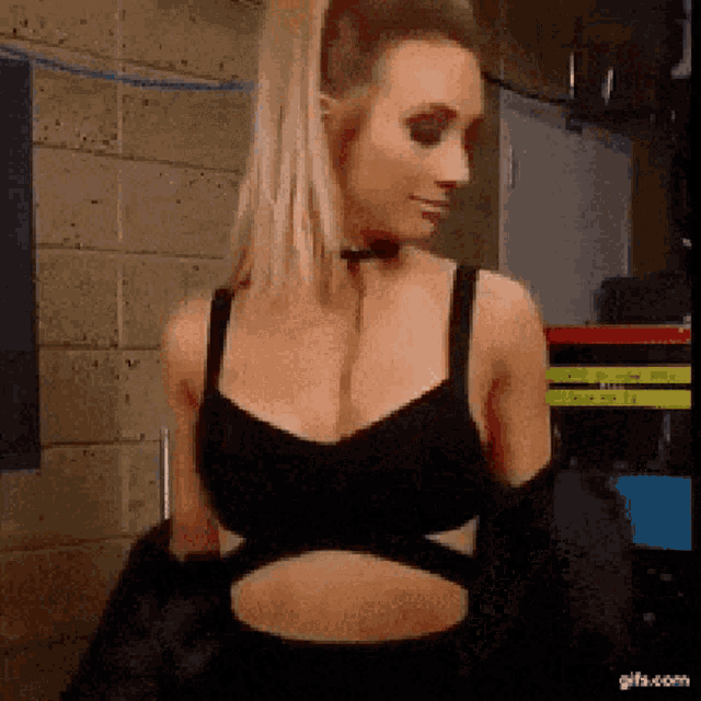 a woman in a black bra is standing in front of a wall .