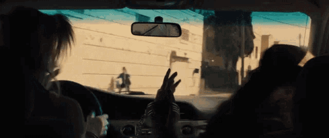 a woman in the back seat of a car is giving the peace sign