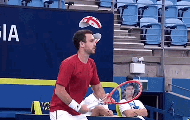 a man in a red shirt is swinging a tennis racket