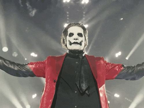 a man in a red jacket and black tie has a mask on